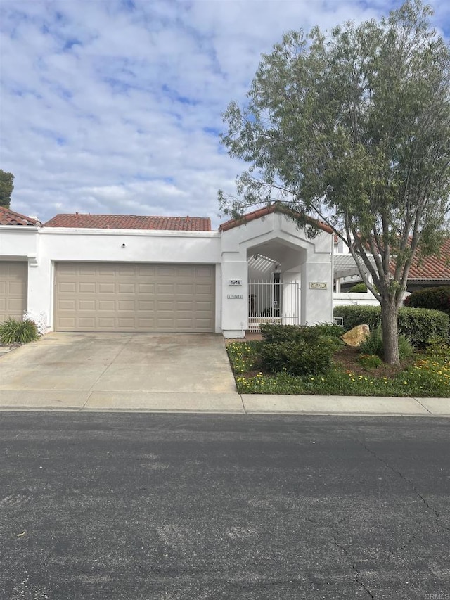 mediterranean / spanish home with an attached garage, a tiled roof, and concrete driveway