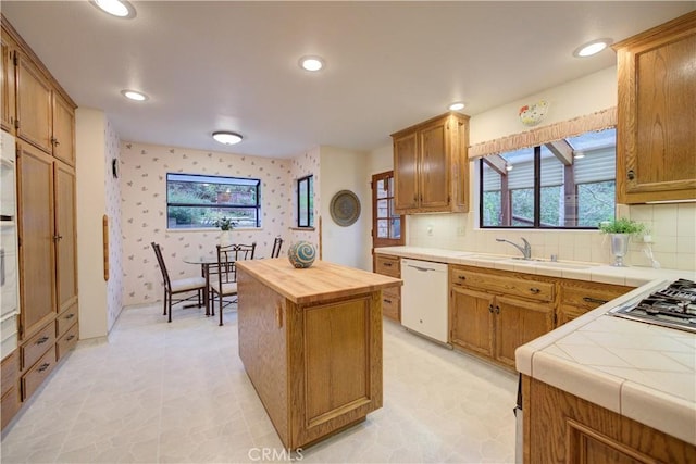 kitchen featuring wallpapered walls, white appliances, a sink, and plenty of natural light