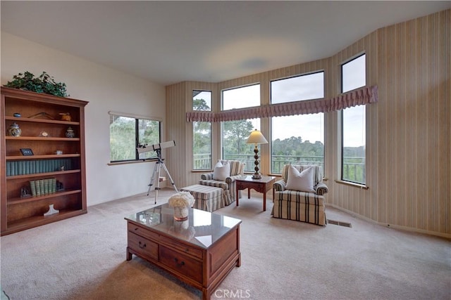 living area with a healthy amount of sunlight, baseboards, light carpet, and visible vents