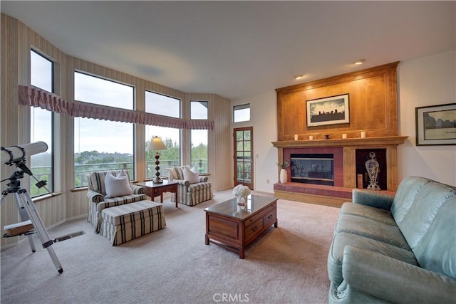 living room featuring a large fireplace, a healthy amount of sunlight, and light colored carpet