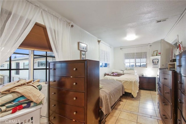 bedroom featuring a textured ceiling, visible vents, and light tile patterned floors