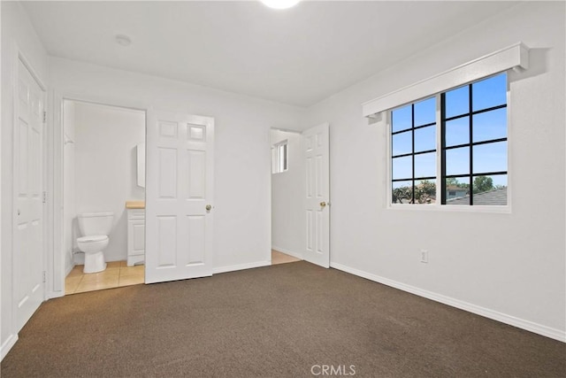 unfurnished bedroom featuring connected bathroom, baseboards, and carpet flooring