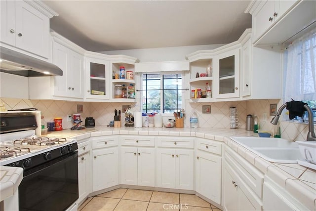 kitchen with open shelves, gas range oven, a sink, and a wealth of natural light
