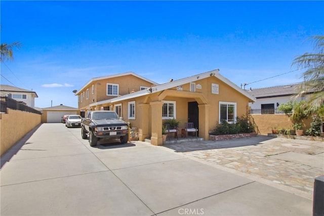view of front facade with fence, an outdoor structure, a detached garage, and stucco siding