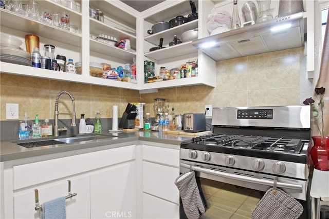 kitchen featuring stainless steel range with gas cooktop, a sink, white cabinetry, backsplash, and under cabinet range hood