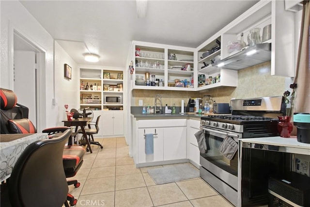 kitchen featuring a sink, decorative backsplash, light tile patterned floors, stainless steel gas stove, and white cabinets