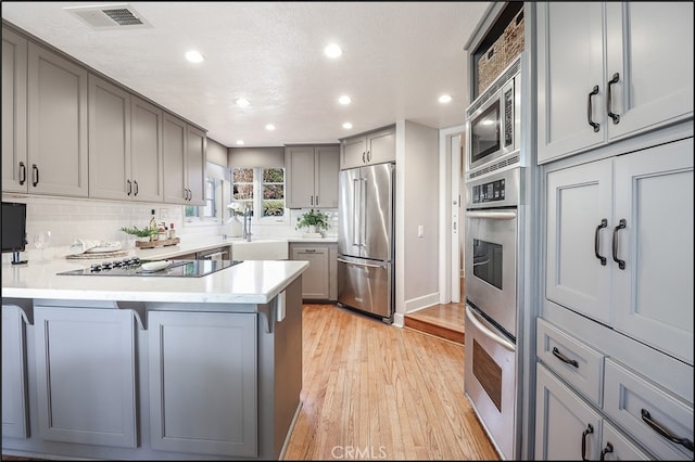 23962 Lanteen Cir, Laguna Niguel, CA 92677 - kitchen featuring appliances with stainless steel finishes, gray cabinetry, a peninsula, recessed lighting, and light wood-type flooring
