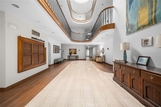 interior space featuring light wood-type flooring, a towering ceiling, and baseboards