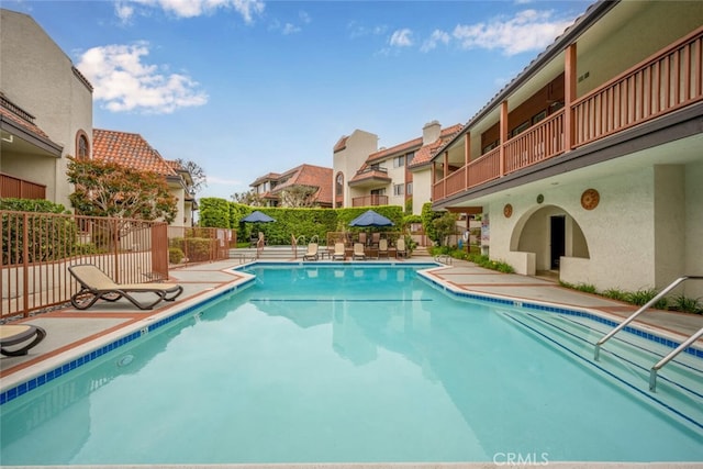 community pool featuring fence, a residential view, and a patio