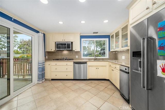 kitchen featuring stainless steel appliances, a sink, cream cabinetry, and light tile patterned floors