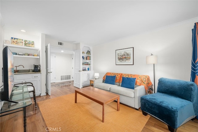 living room featuring recessed lighting, visible vents, light wood finished floors, and ornamental molding
