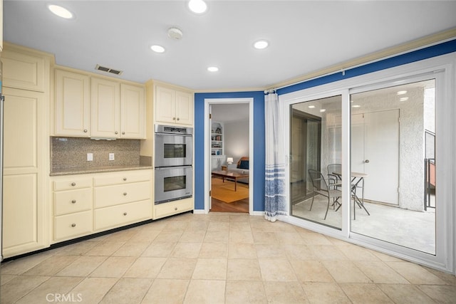 kitchen featuring recessed lighting, double oven, visible vents, light stone countertops, and cream cabinets