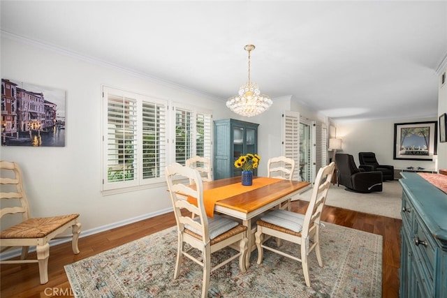 dining space with dark wood finished floors, an inviting chandelier, crown molding, and baseboards