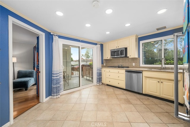 kitchen featuring cream cabinets, crown molding, and stainless steel appliances