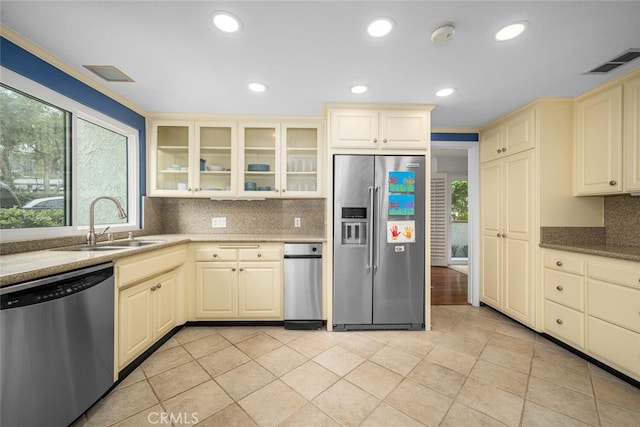 kitchen with a sink, tasteful backsplash, visible vents, cream cabinetry, and appliances with stainless steel finishes