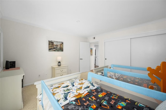 carpeted bedroom with baseboards, ornamental molding, visible vents, and a closet