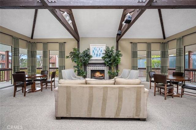 living room with a warm lit fireplace, carpet floors, and lofted ceiling with beams