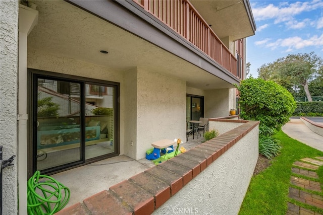 entrance to property with a patio area, a balcony, and stucco siding