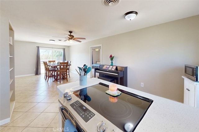 dining area featuring baseboards, a ceiling fan, visible vents, and light tile patterned floors