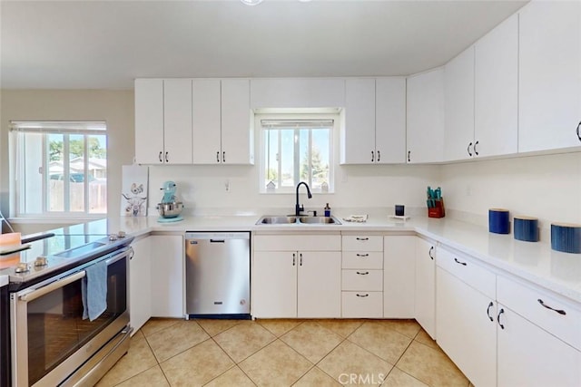 kitchen featuring white cabinets, a sink, light tile patterned flooring, light countertops, and appliances with stainless steel finishes