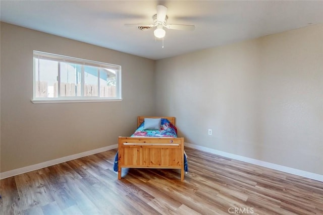 bedroom featuring ceiling fan, baseboards, and wood finished floors