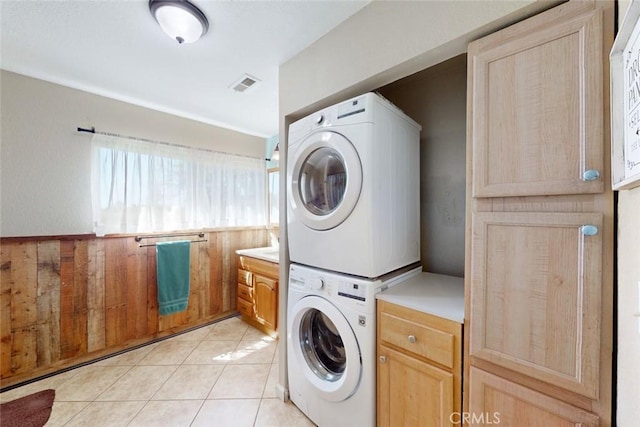 laundry room with visible vents, stacked washer and clothes dryer, and light tile patterned floors