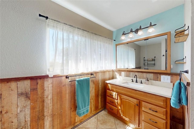 bathroom with a textured wall, vanity, and tile patterned flooring