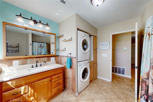 laundry room with stacked washer and dryer, a sink, visible vents, and light tile patterned floors