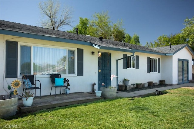 back of property with a yard and stucco siding