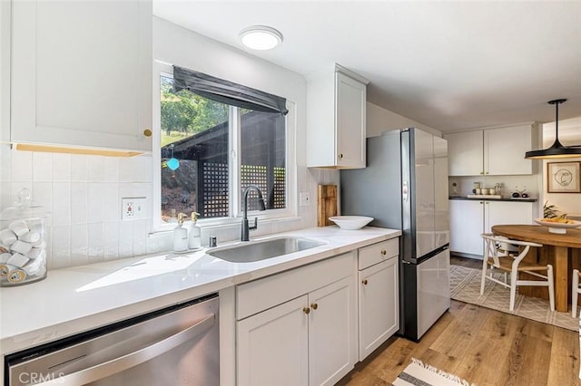 28383 Shady Oaks Rd, Clovis, CA 93619 - kitchen with white cabinets, light wood finished floors, stainless steel appliances, a sink, and decorative backsplash