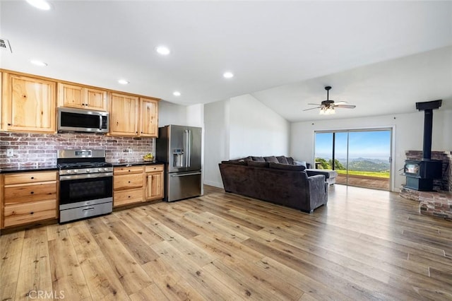 28383 Shady Oaks Rd, Clovis, CA 93619 - kitchen with dark countertops, a wood stove, light wood-style floors, decorative backsplash, and appliances with stainless steel finishes