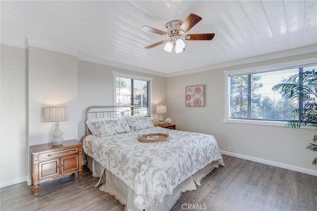 bedroom with wood finished floors, crown molding, baseboards, and a ceiling fan