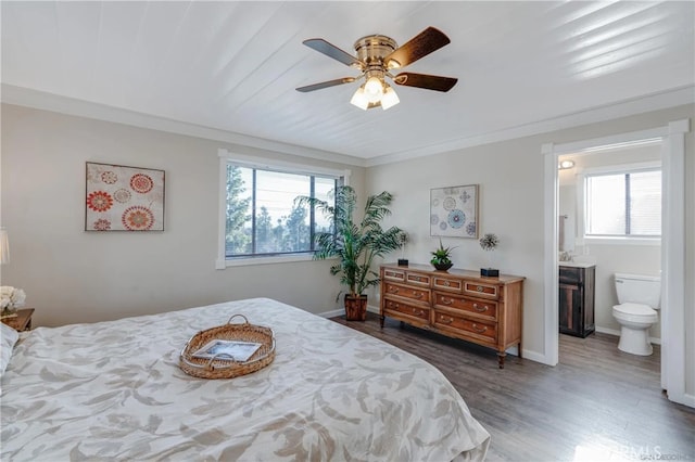 bedroom with baseboards, wood finished floors, connected bathroom, and multiple windows