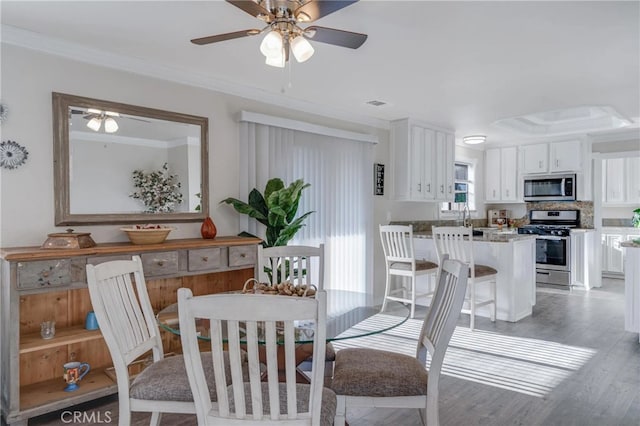 dining area with ceiling fan, ornamental molding, visible vents, and light wood-style flooring