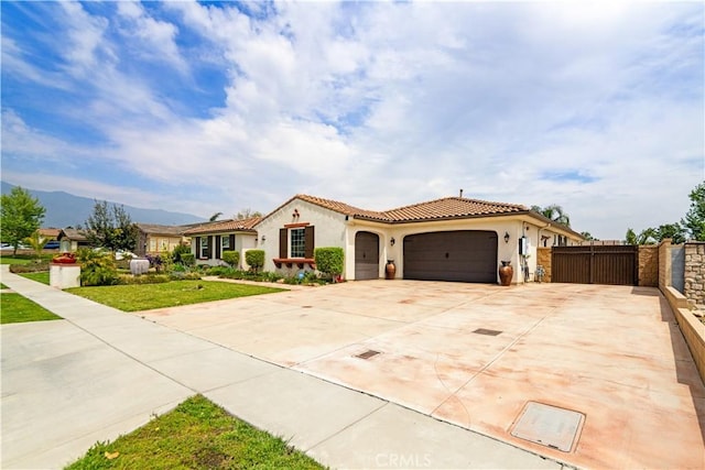 mediterranean / spanish house with a tile roof, driveway, fence, a garage, and stucco siding