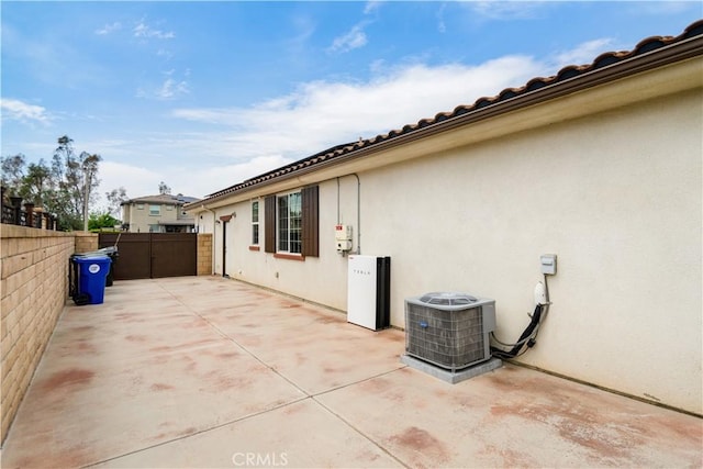 view of home's exterior with central AC, fence, a patio, and stucco siding