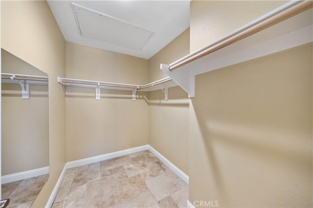walk in closet featuring stone finish floor