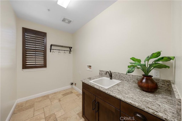 washroom featuring stone tile floors, visible vents, a sink, baseboards, and washer hookup
