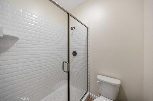full bath with toilet, baseboards, and a stall shower
