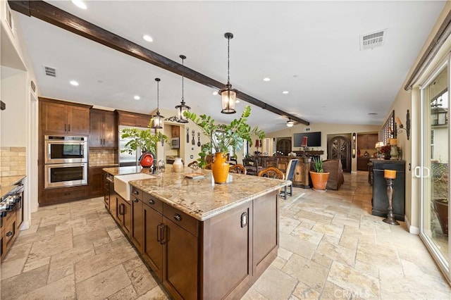 kitchen with a sink, lofted ceiling with beams, stone tile floors, stainless steel double oven, and backsplash