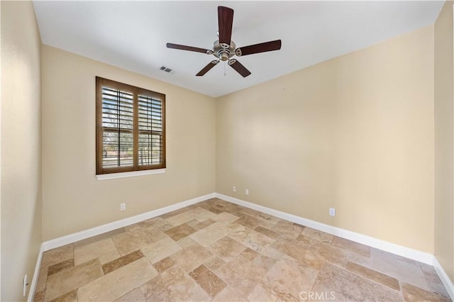 empty room featuring stone tile floors, baseboards, and ceiling fan