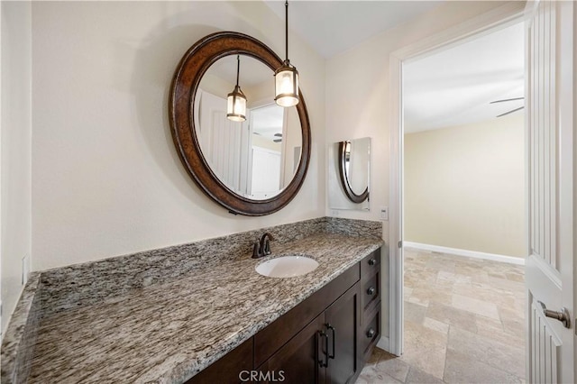 bathroom with baseboards, vanity, and stone finish floor