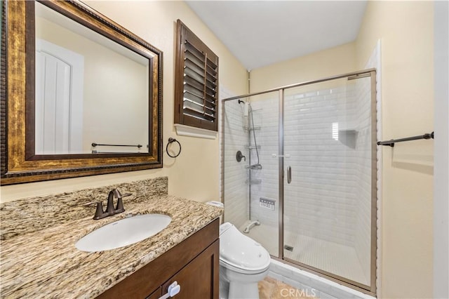 bathroom featuring vanity, a shower stall, and toilet