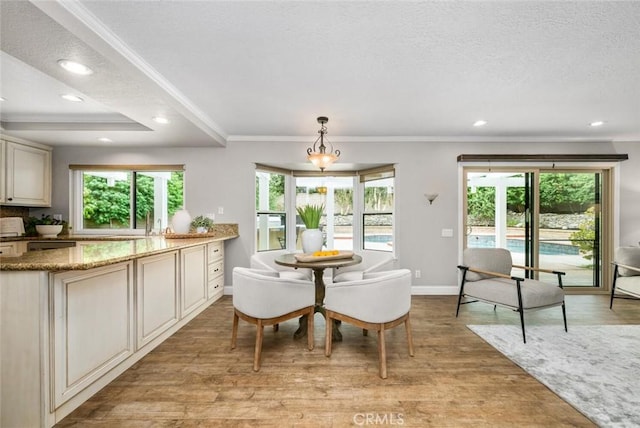 dining area with baseboards, crown molding, light wood finished floors, and recessed lighting