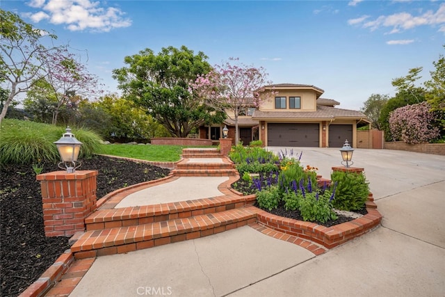 view of front of home featuring stucco siding, driveway, a tiled roof, and a garage