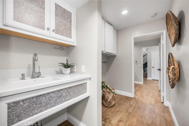 interior space with baseboards, a sink, and light wood-style floors