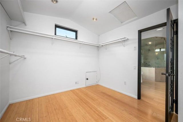 spacious closet featuring attic access, lofted ceiling, and light wood-type flooring