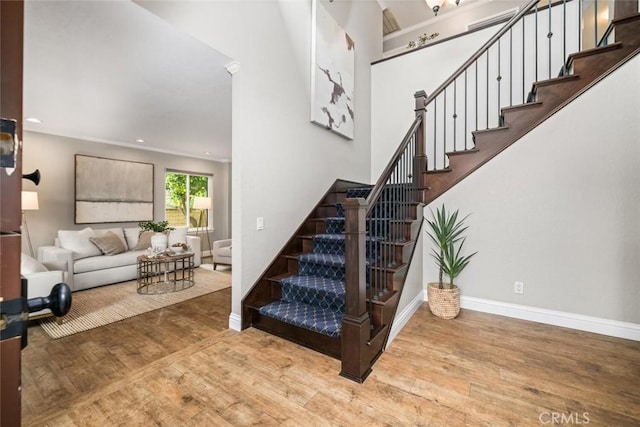 stairway with baseboards, wood finished floors, and recessed lighting