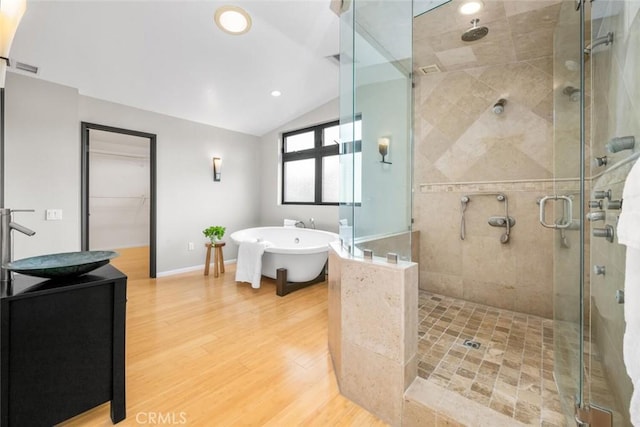 full bath featuring a freestanding bath, wood finished floors, lofted ceiling, and a stall shower