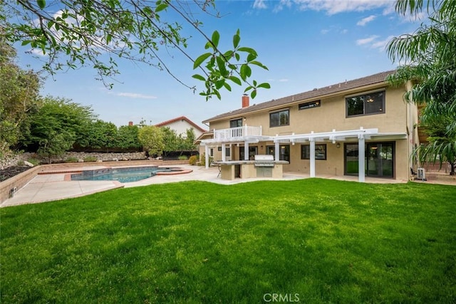 back of property featuring an outdoor pool, an outdoor kitchen, a lawn, a patio, and stucco siding